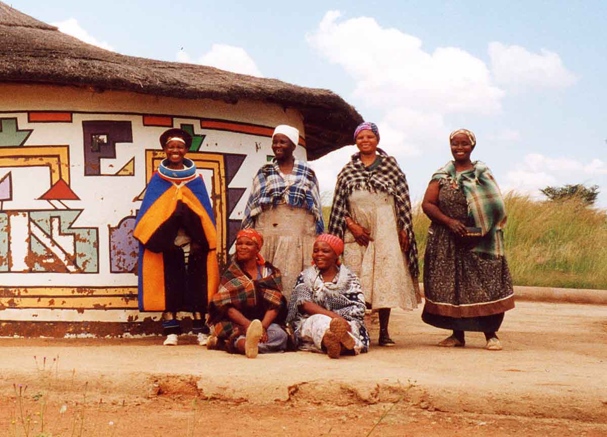 Ndebele women in front of a patterned house